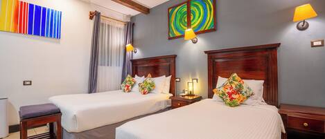 A hotel room with two beds, a wooden headboard, a nightstand, a lamp, and a ceiling fan.