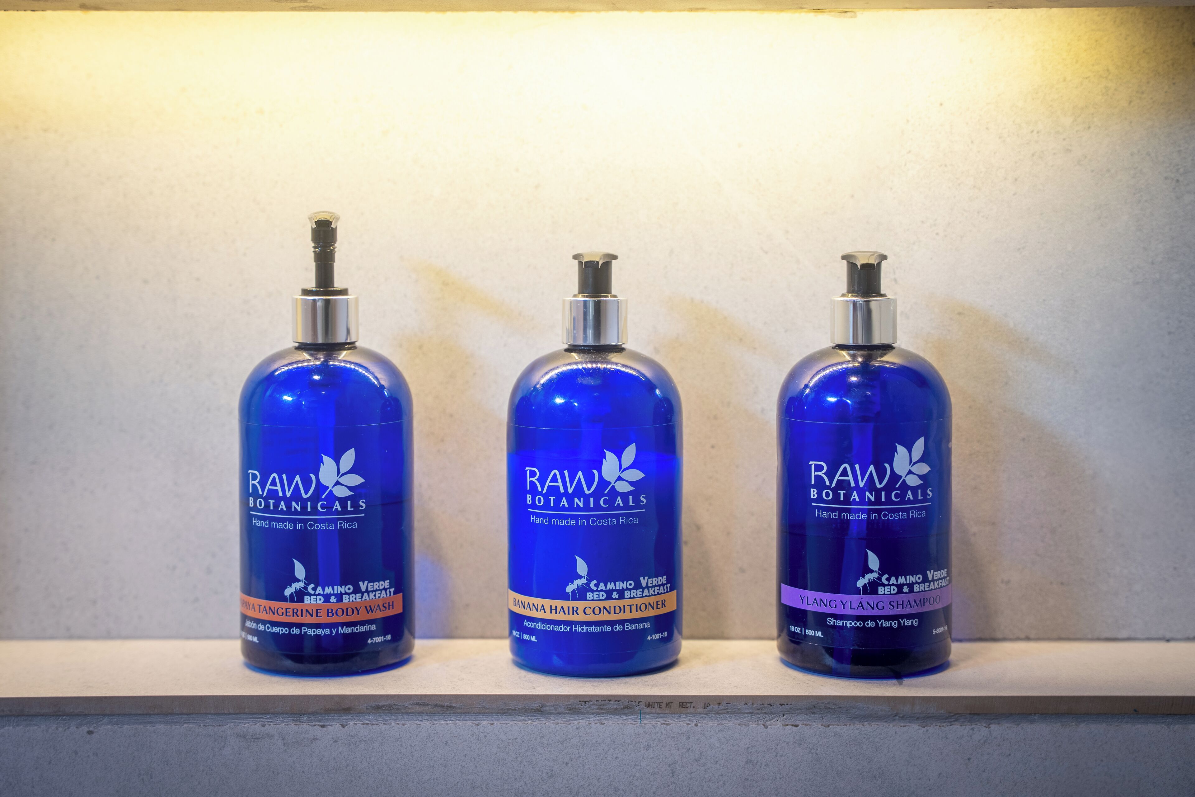 Three bottles of bath products on a shelf.