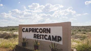 A sign for Capricorn Restcamp with three potted plants in front.