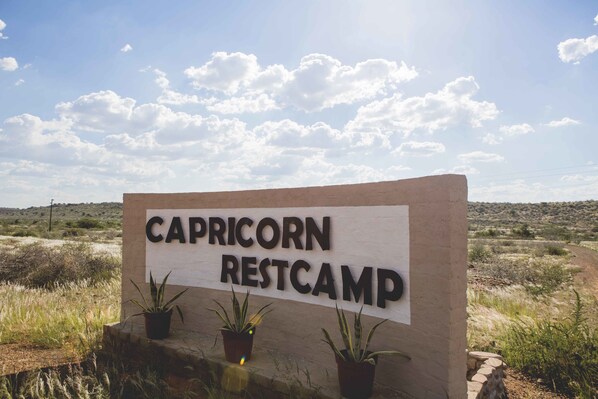 A sign for Capricorn Restcamp with three potted plants in front.