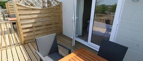 A wooden deck with a table and chairs, a sliding glass door, and a wooden fence.