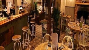 Ein gemütliches Restaurant mit Holztischen und -stühlen, einer Bar und einem Kamin.