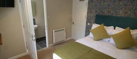 A bedroom with a bed, a radiator, a door, and a wall with a floral pattern.