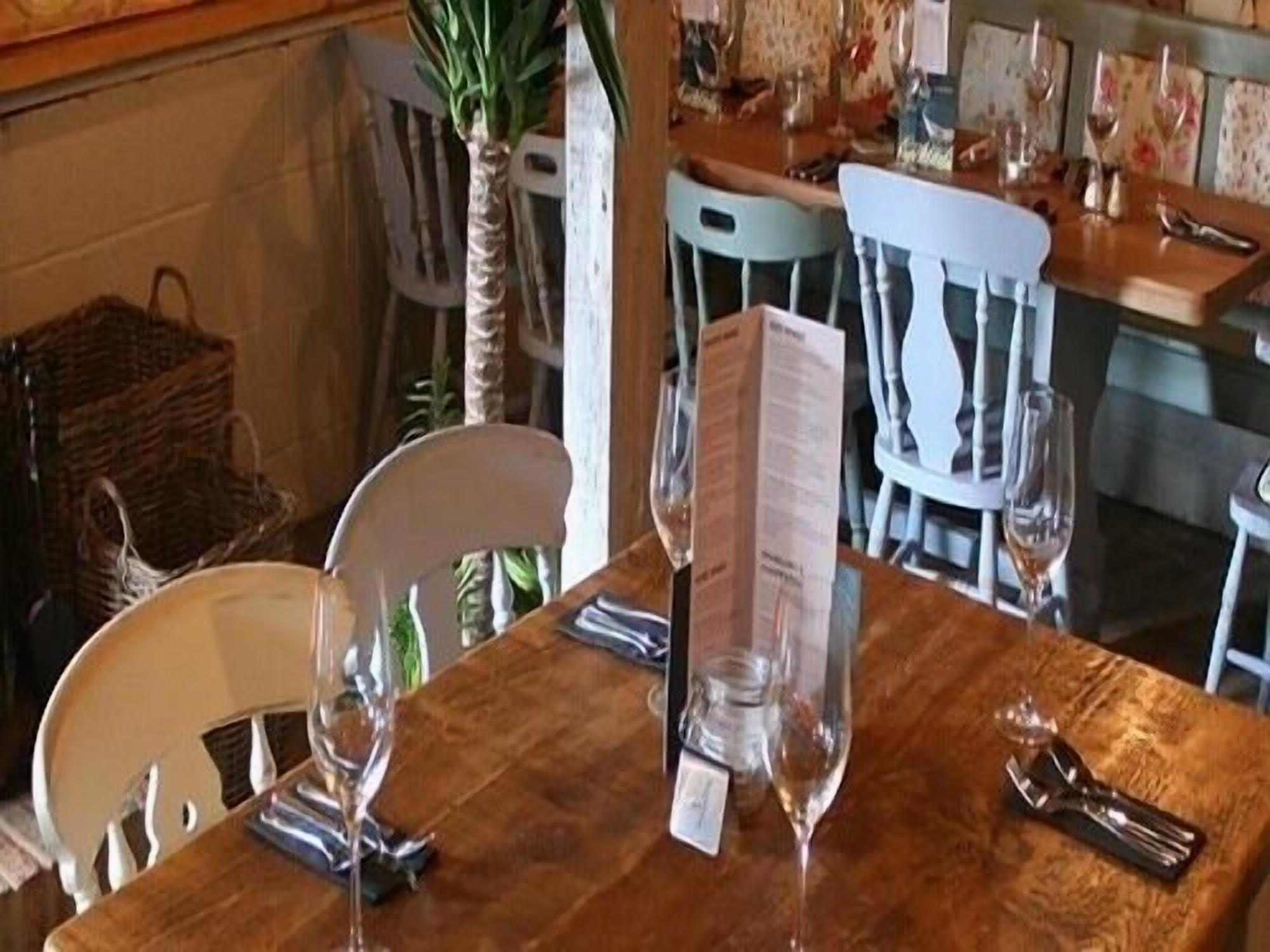 Una mesa de comedor con un menú, copas de vino y cubiertos.