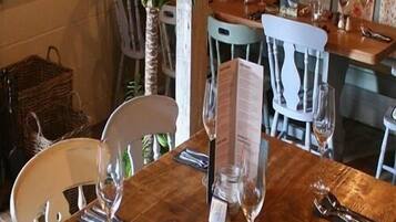 Una mesa de comedor con un menú, copas de vino y cubiertos.