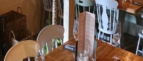 Una mesa de comedor con un menú, copas de vino y cubiertos.