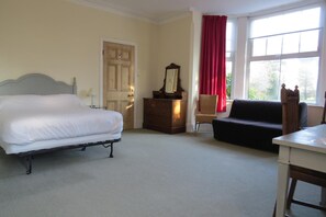 A bedroom with a bed, a dresser, a chair, a sofa, and a table. - Furtho Manor Farm (Milton Keynes)
