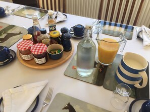 A breakfast table set with various condiments, a glass of orange juice, and a pitcher of water. - Furtho Manor Farm (Milton Keynes)
