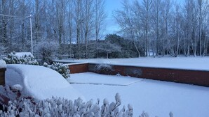 Un espacio exterior cubierto de nieve con una estructura de ladrillo y árboles sin hojas.