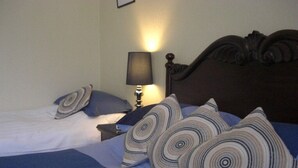 Una habitación de hotel con una cama, una mesita de noche con lámpara y un cabecero de madera.