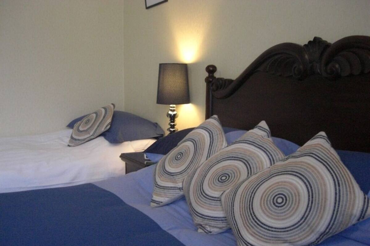 A hotel room with a bed, a nightstand with a lamp, and a wooden headboard.
