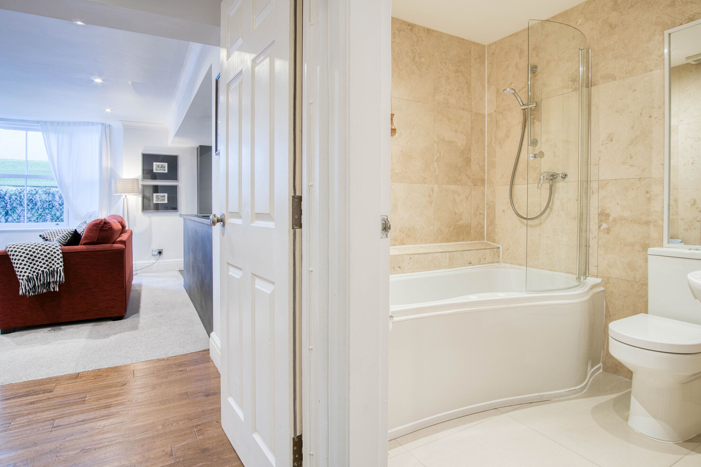 Un baño moderno con ducha de vidrio, una bañera blanca y un inodoro.