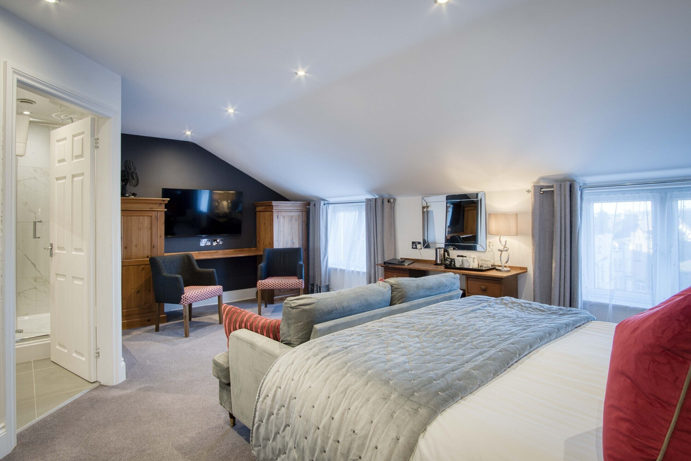 A bedroom with a large bed, a TV, a desk, and a chair.