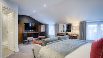 A bedroom with a large bed, a TV, a desk, and a chair.