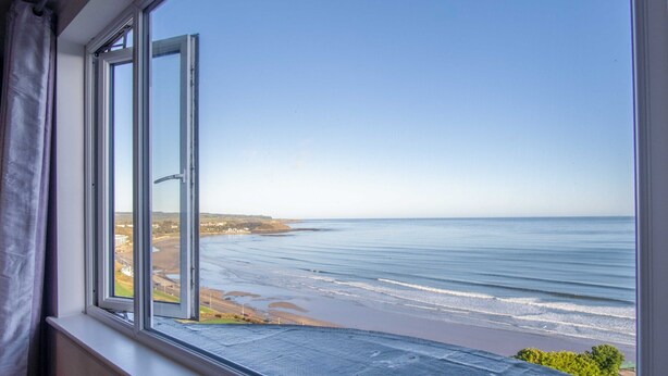 Ein Fenster mit Blick auf einen Strand und den Ozean.