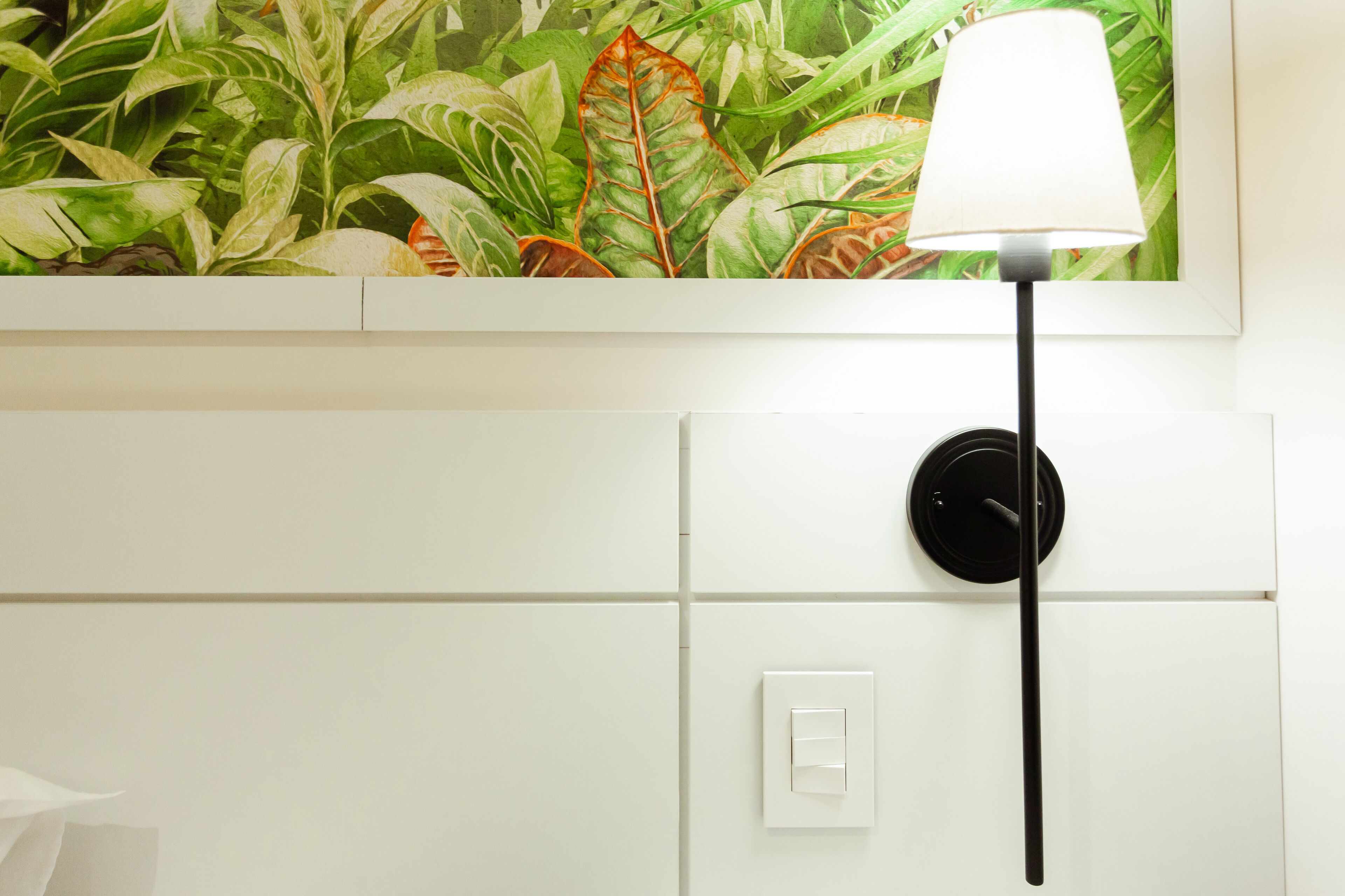 A wall with a white cabinet, a switch, and a black lamp.