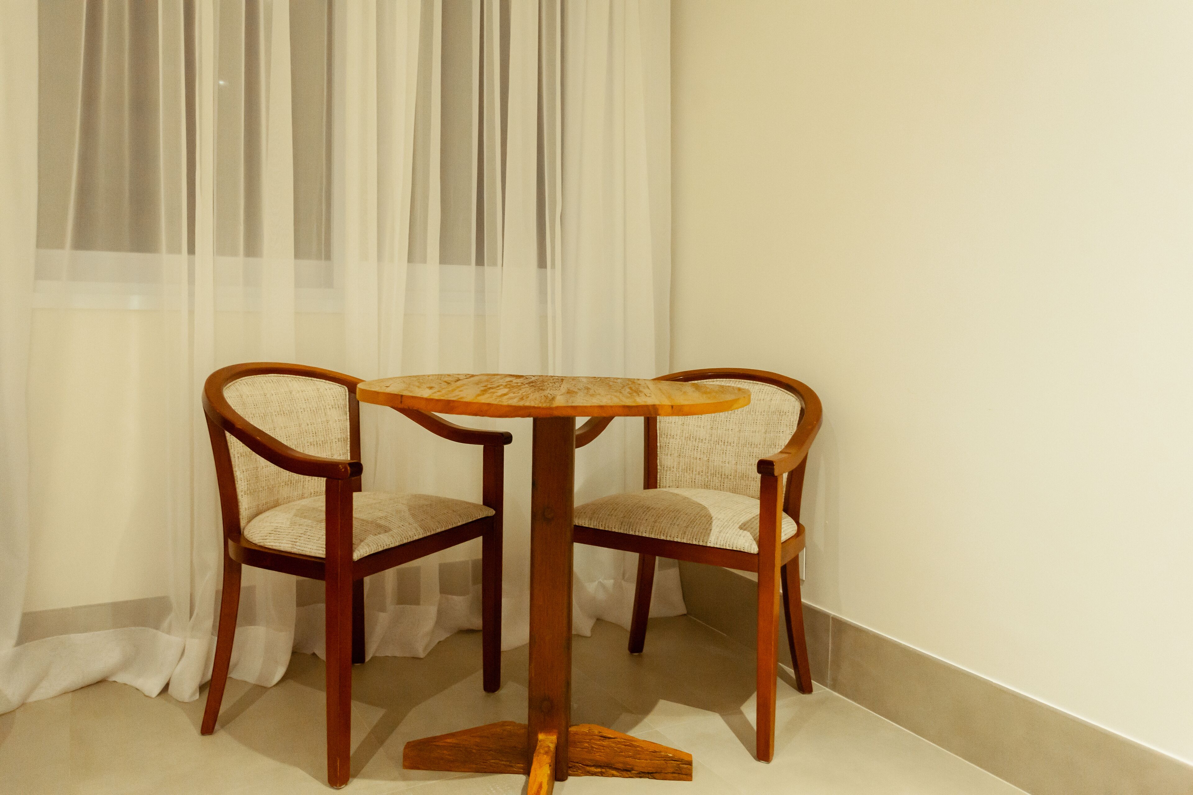 A corner room with a round wooden table and two wicker chairs.