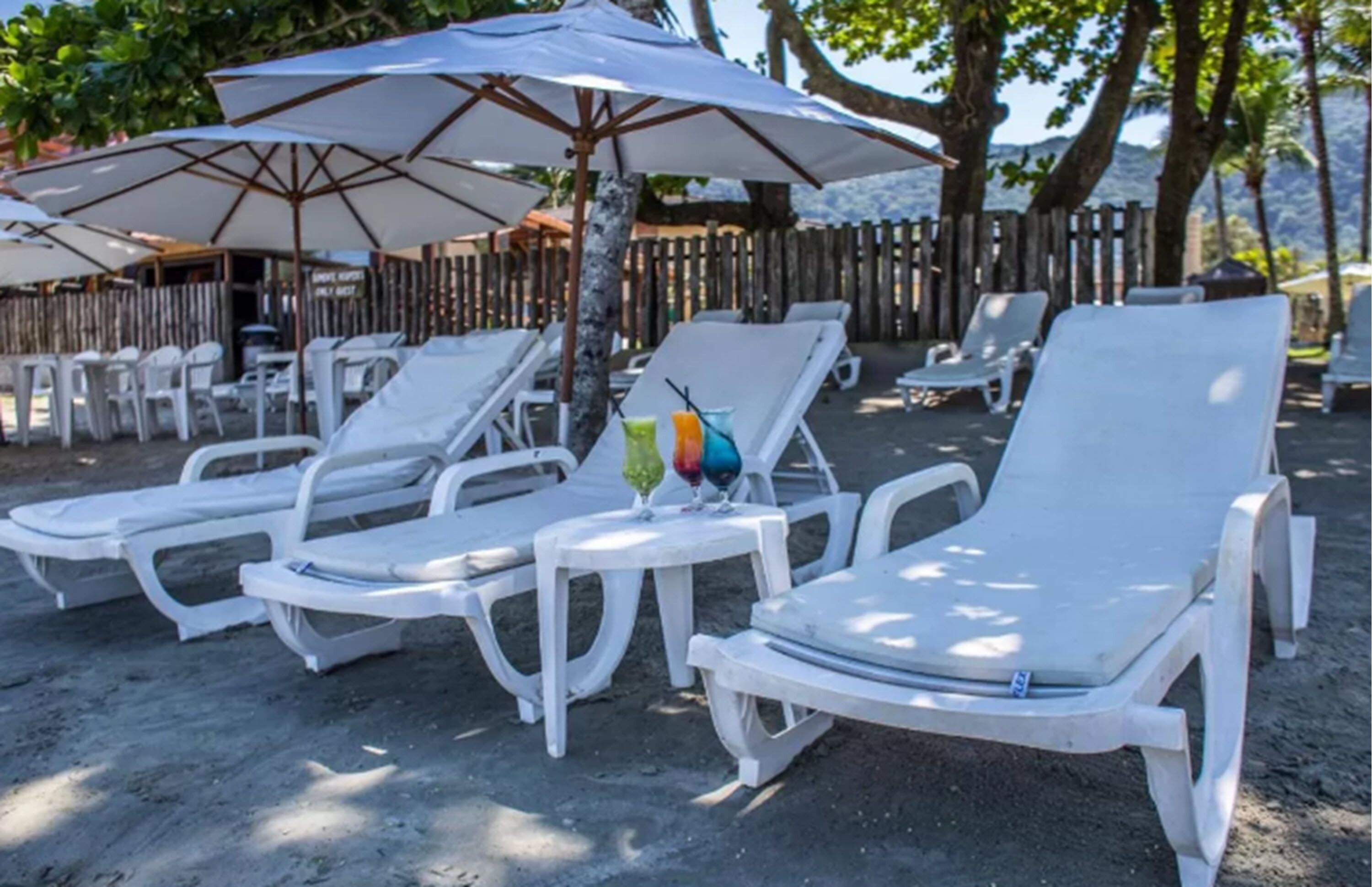 Sillones de exterior y sombrillas en una zona arenosa, probablemente una playa o un complejo turístico.