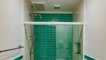 Een kleine, afgesloten douchecabine met groene tegels en een wit toilet.