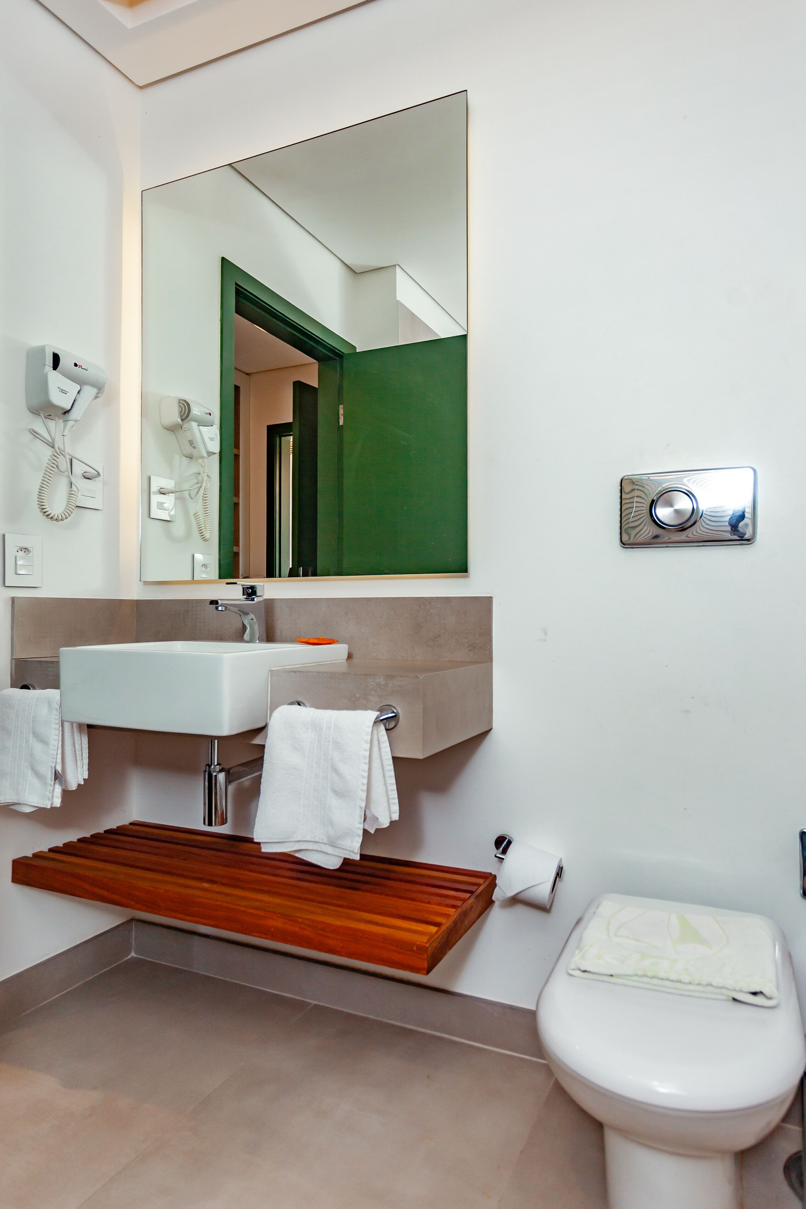 A modern bathroom with a white sink, mirror, and toilet.