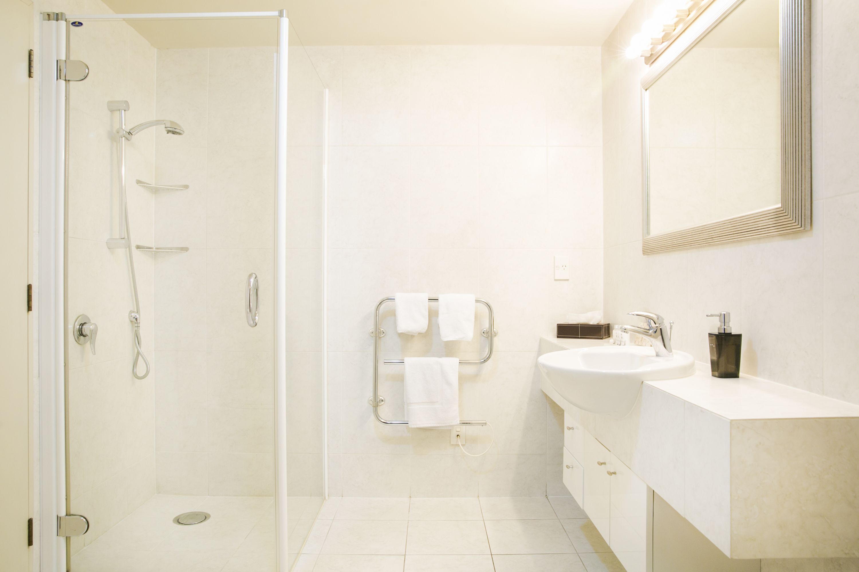 Un baño moderno con cabina de ducha de vidrio, un lavamanos blanco y un espejo.