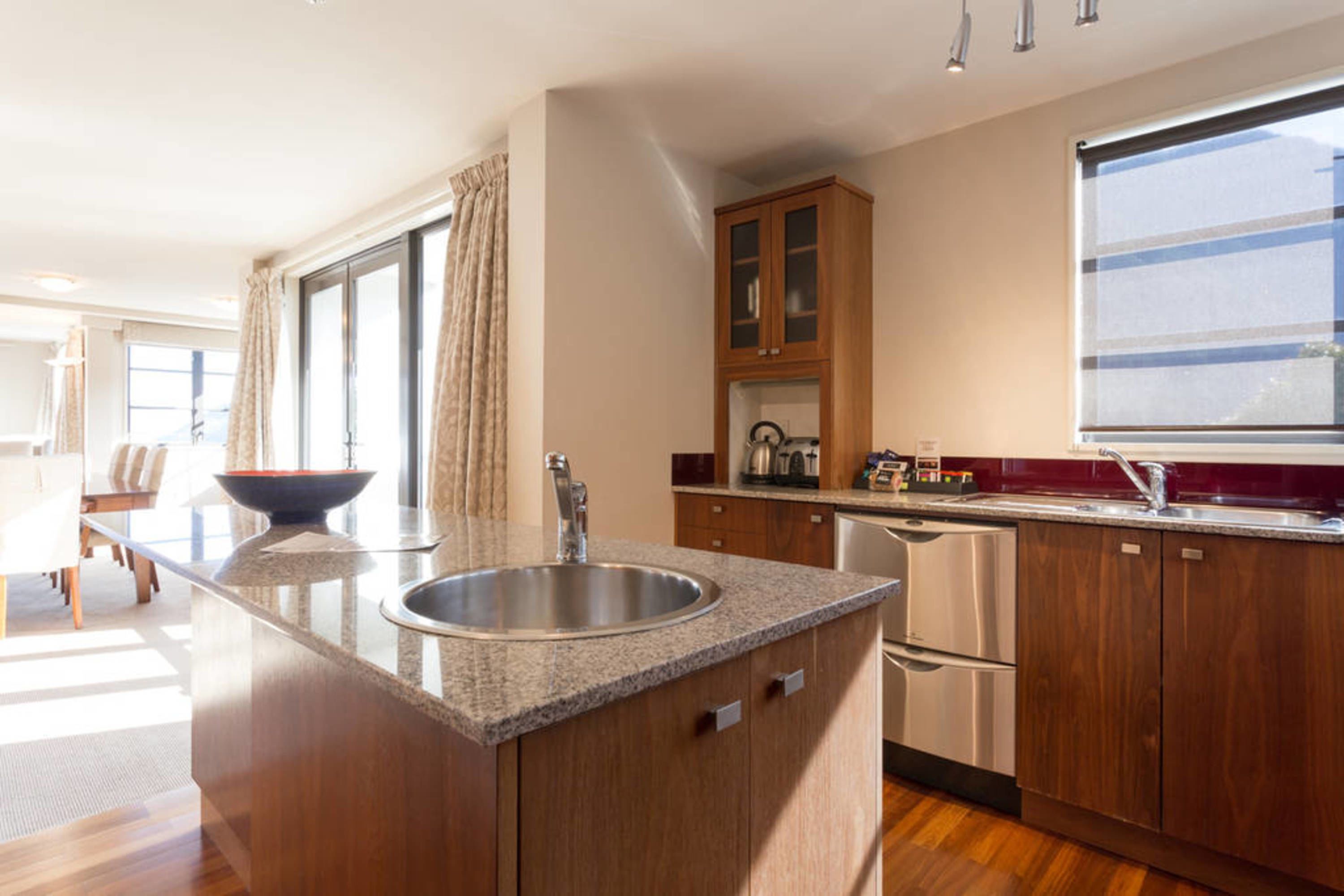 A modern kitchen with granite countertops, stainless steel appliances, and wooden cabinets.