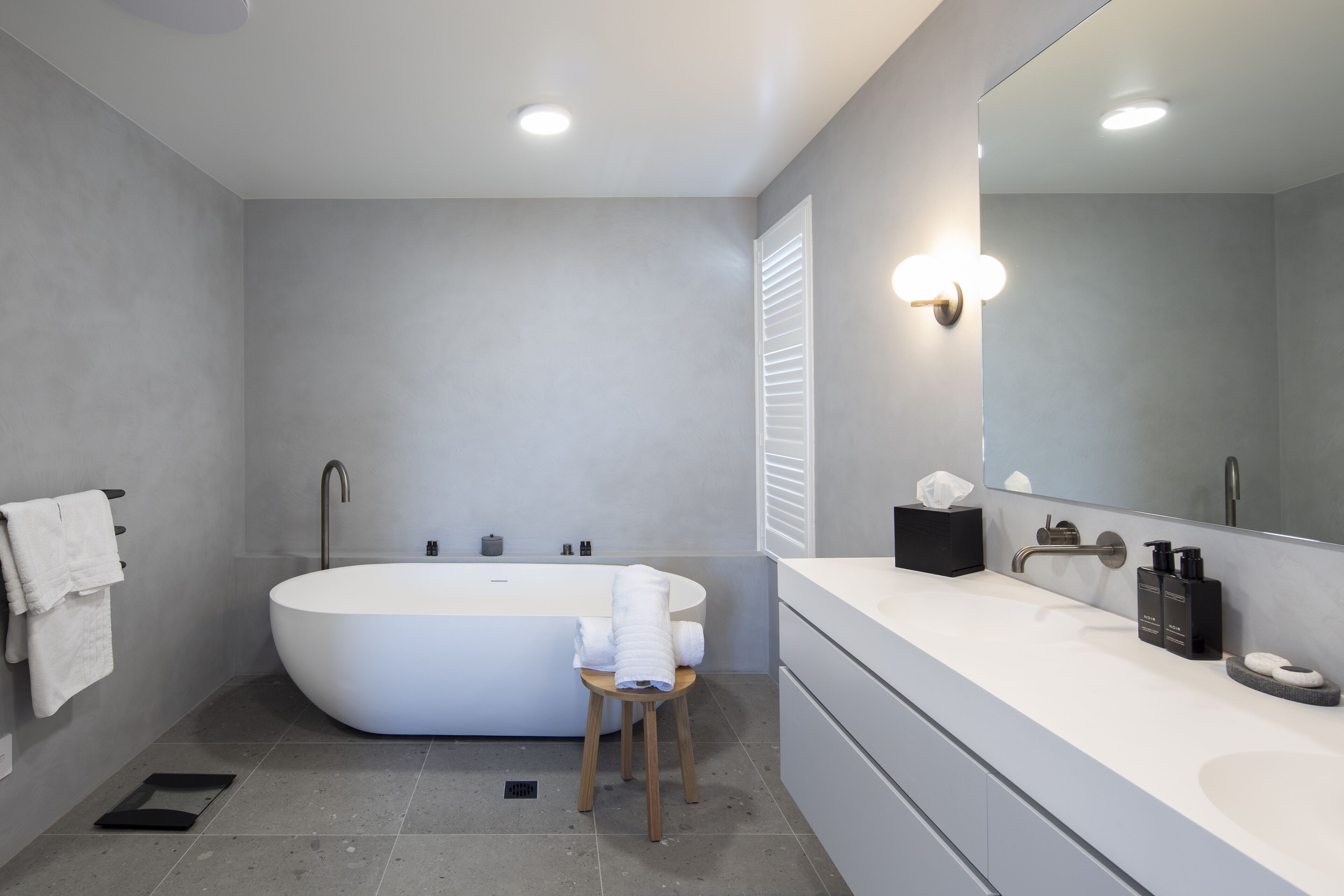 Un baño moderno con una bañera independiente, un tocador con un espejo grande y un perchero para toallas.