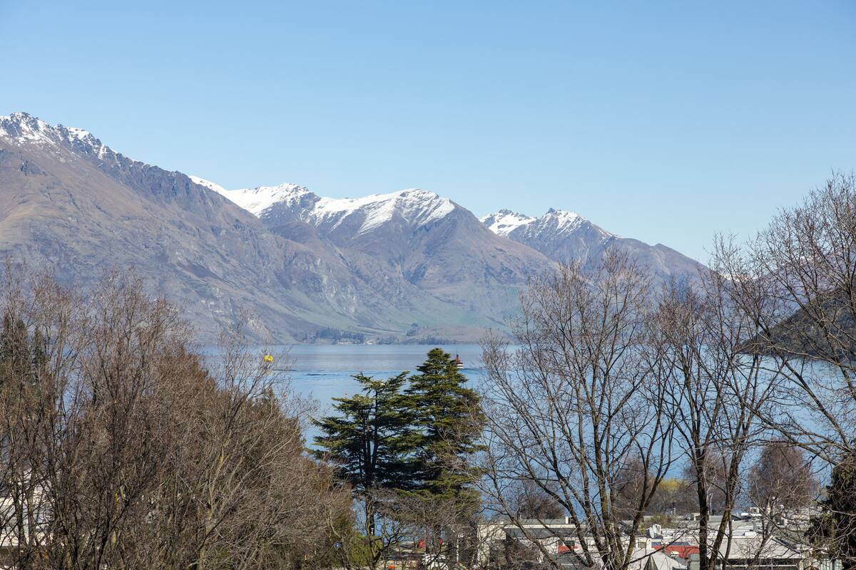 A mountainous landscape with a lake and sparse trees in the foreground.