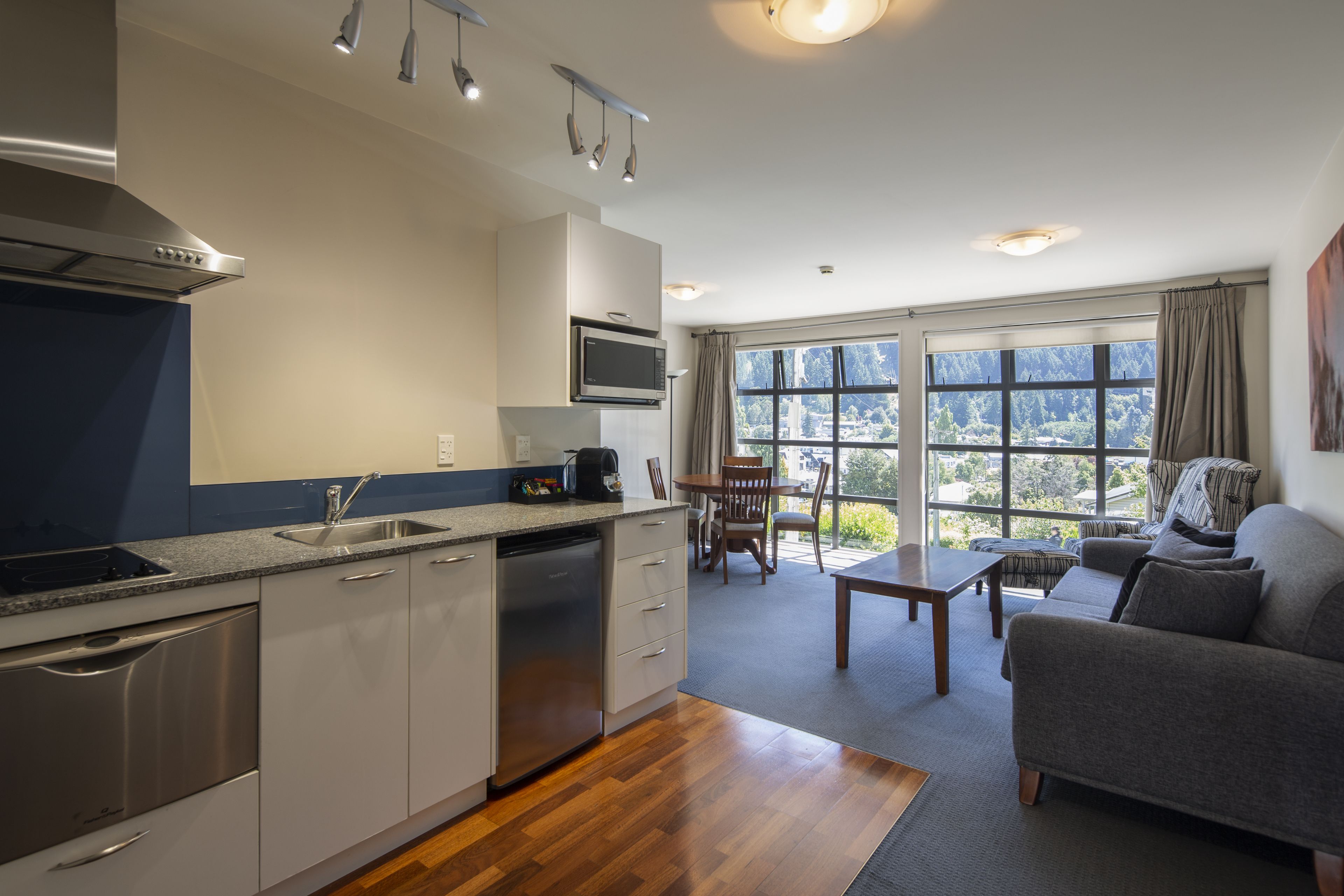 A modern kitchen with stainless steel appliances, a dining area with a table and chairs, and a sofa.