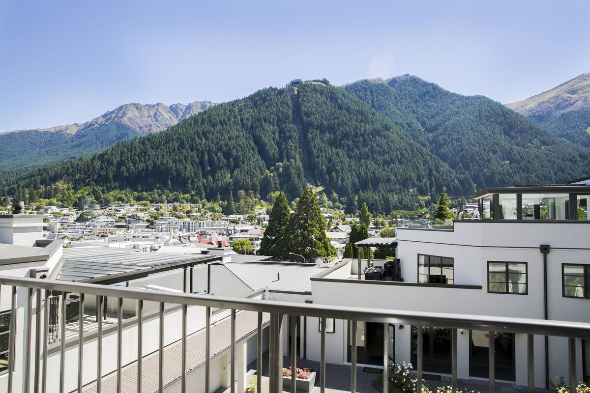 A modern building with a flat roof, large windows, and a balcony with a railing.