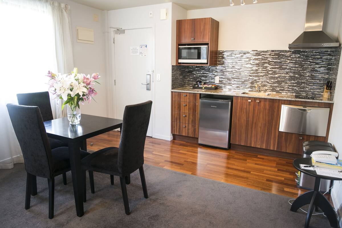 A modern kitchen with wooden cabinets, a stainless steel dishwasher, and a tiled backsplash.