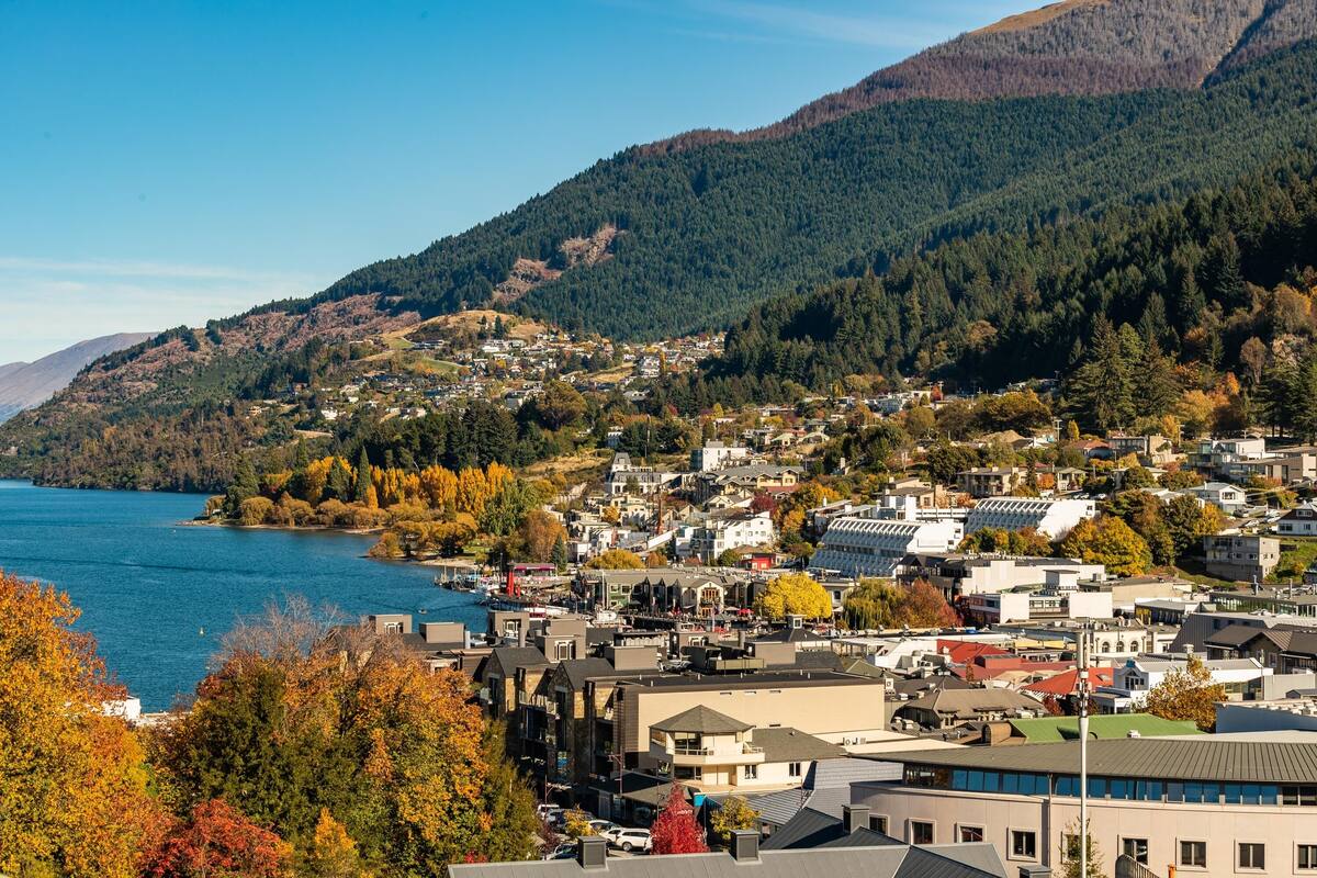 A coastal town with buildings along the waterfront, surrounded by hills and a body of water.