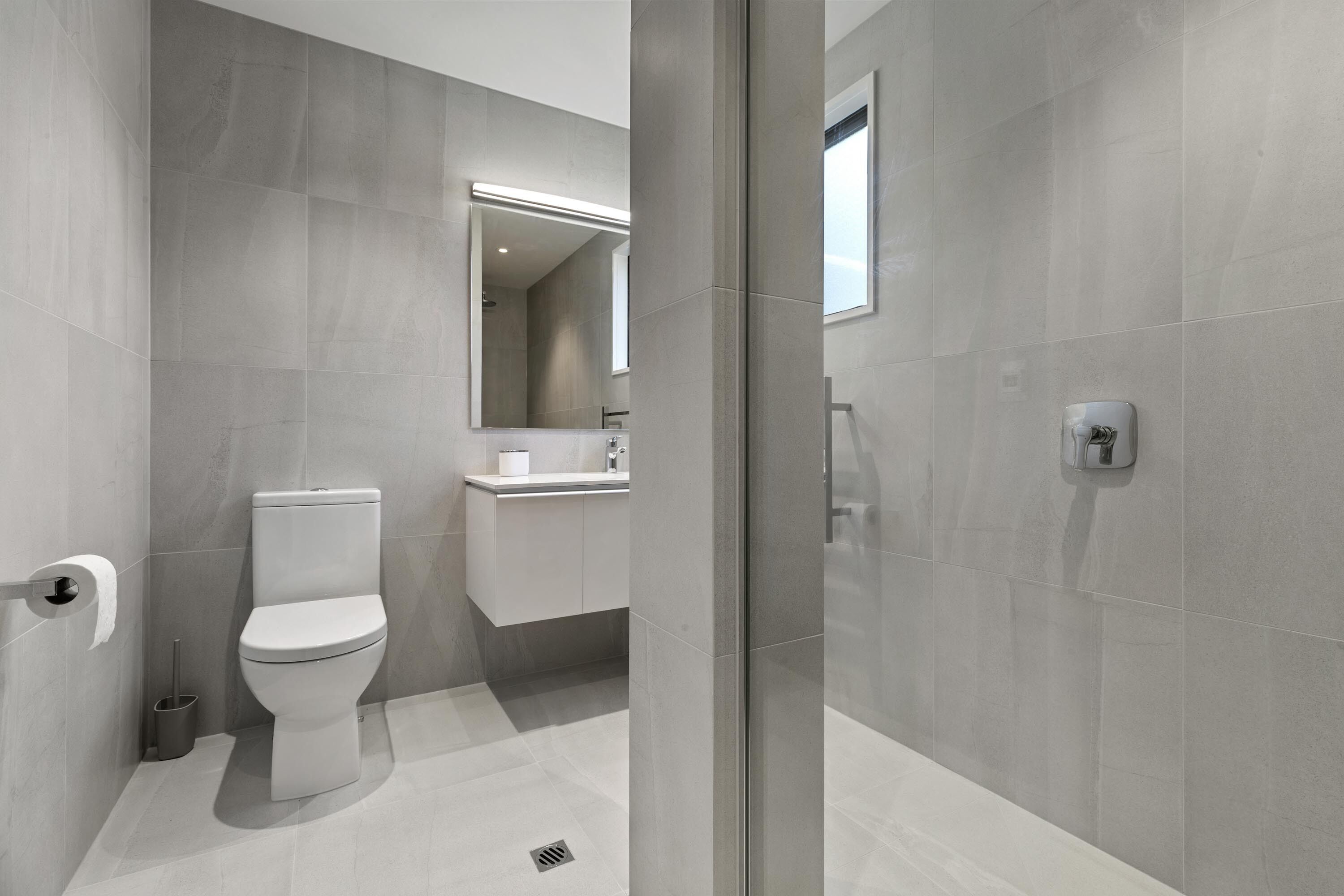 A modern bathroom with a toilet, sink, and mirror.