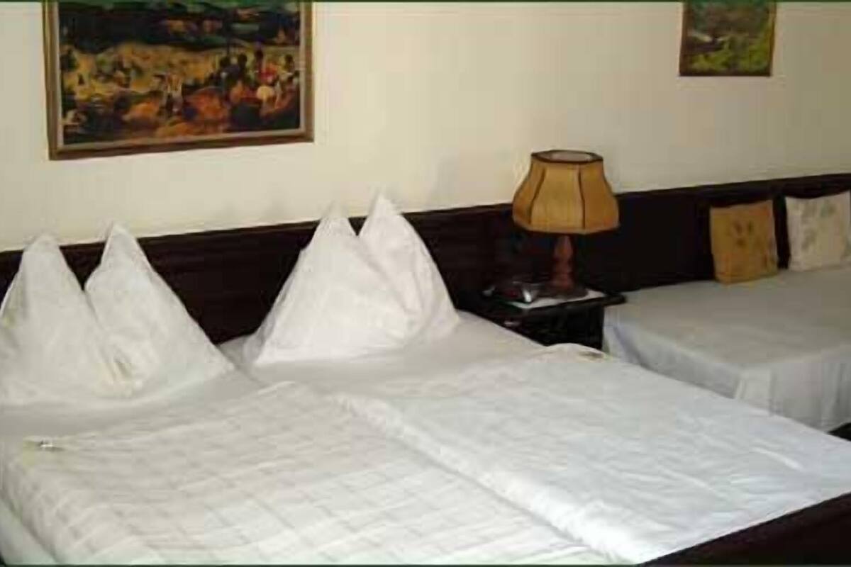 Una habitación de hotel con dos camas, una mesita de noche y una lámpara.