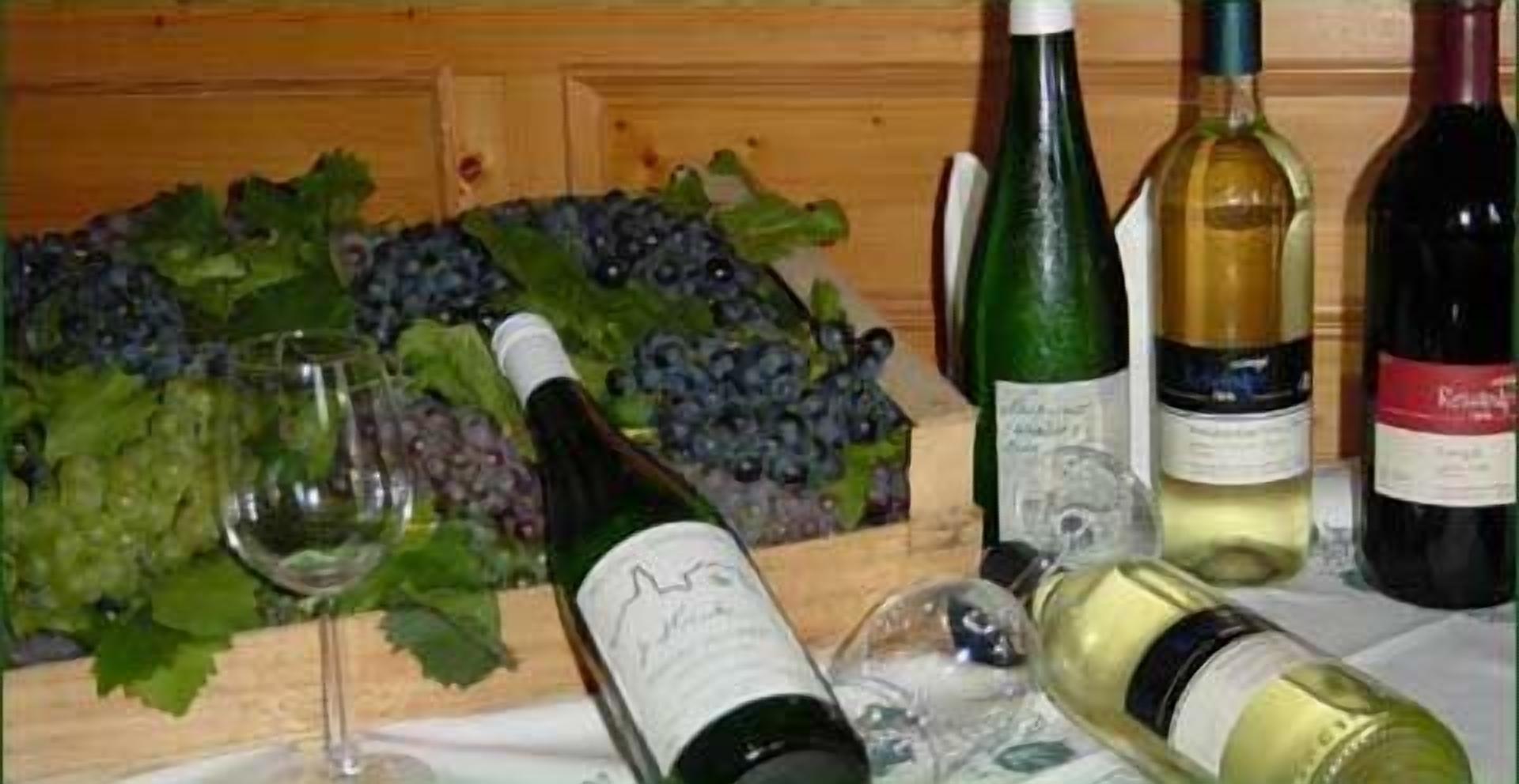 Un tavolo con diverse bottiglie di vino e una ciotola di uva.