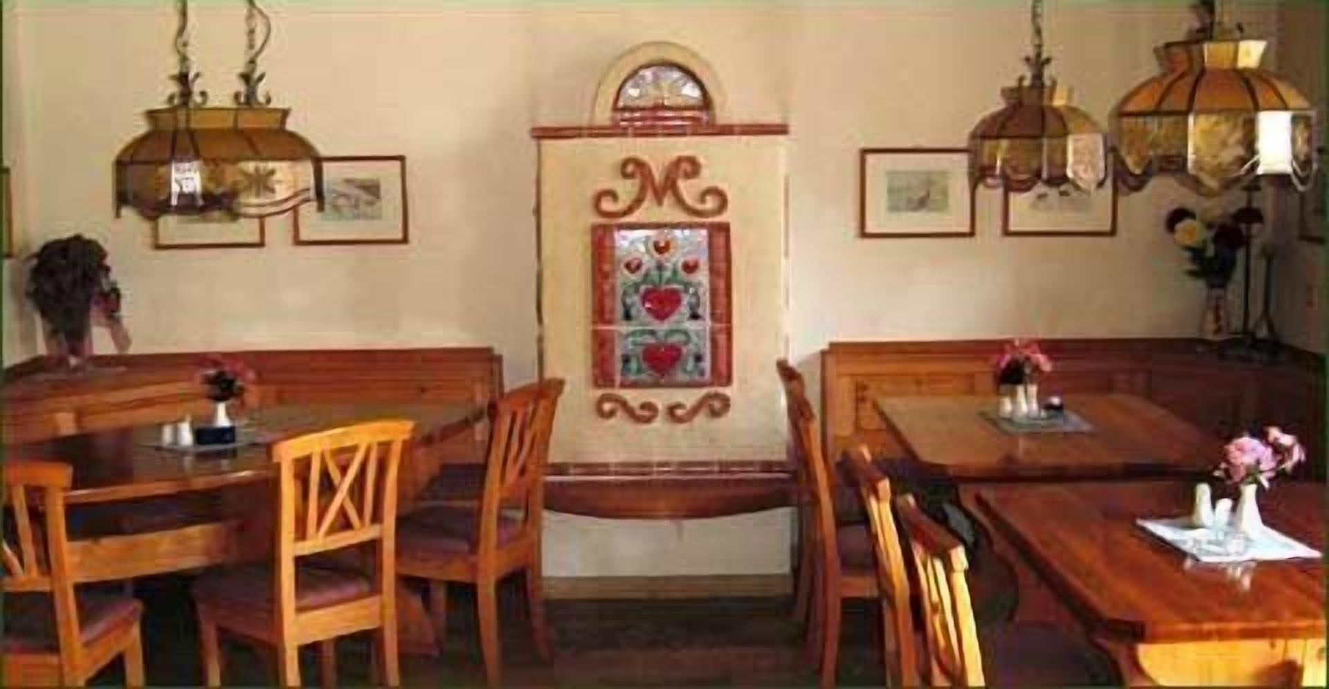 A dining area with wooden tables and chairs, a decorative wall panel, and hanging lamps.