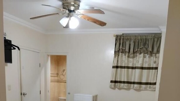 A bedroom with a bed, a desk, a chair, a ceiling fan, and a window with curtains. - Jeshua Inn Guayaquil (Guayaquil)
