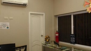 A hotel room with a desk, chair, air conditioning unit, window, and a minibar. - Jeshua Inn Guayaquil (Guayaquil)