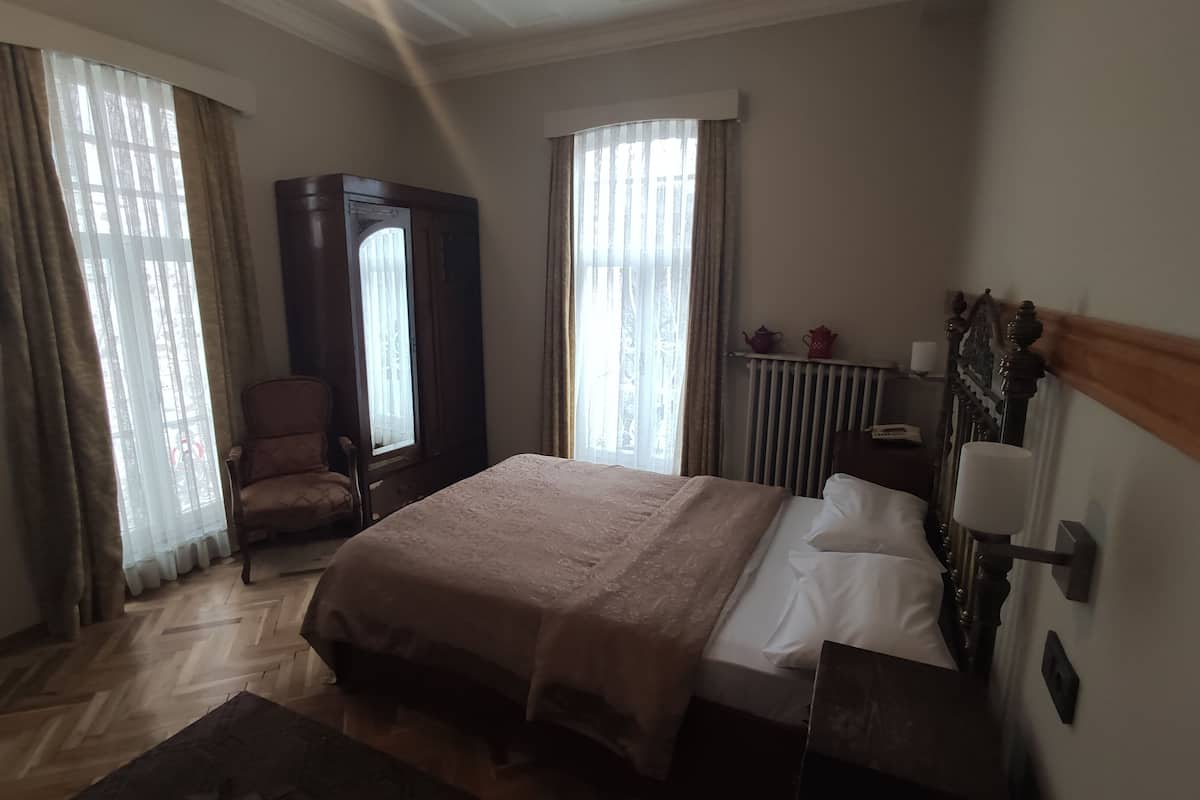 Ein Hotelzimmer mit einem großen Bett, einem Sessel, einem Kleiderschrank und einer Heizung.