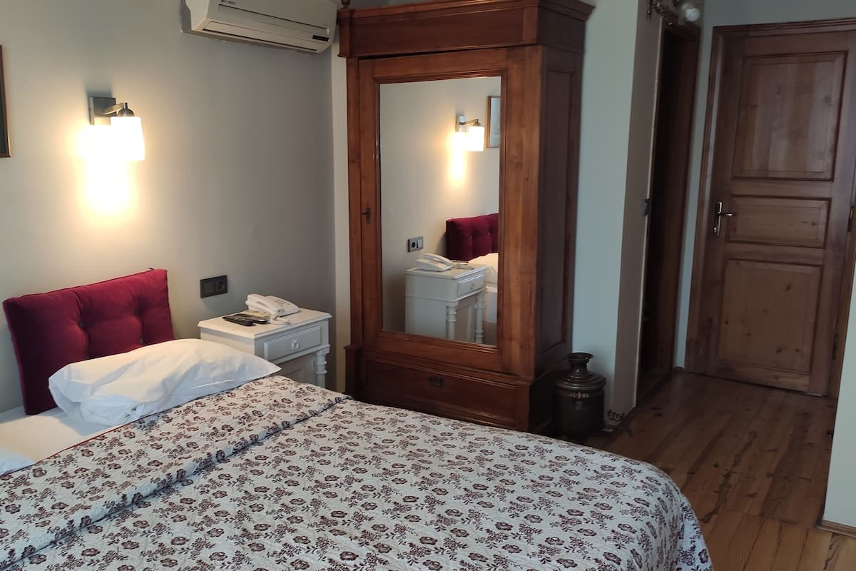 Ein Schlafzimmer mit einem großen Bett, einem Nachttisch, einem Spiegel und einer Holztür.