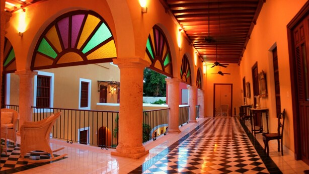 A corridor with tiled flooring, arched columns, and a checkered floor pattern.