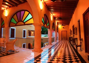 A corridor with tiled flooring, arched columns, and a checkered floor pattern. - Casa Don Gustavo Boutique Hotel (Campeche)