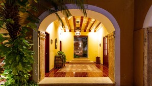 A well-lit hallway with a tiled floor, an arched entrance, and a decorative ceiling light.