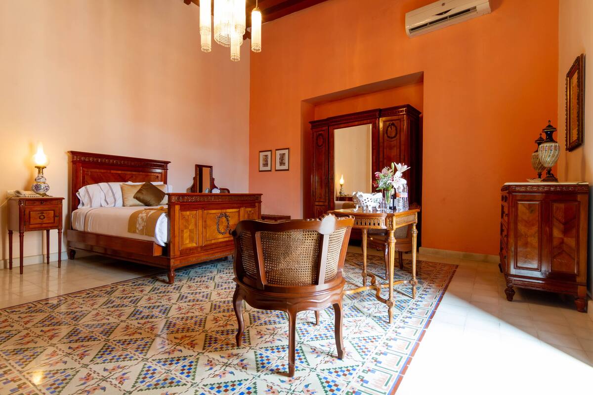 A room with a bed, a chair, a dresser, and a mirror.
