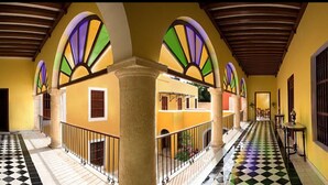 A corridor with a checkered floor, arched ceilings, and a central column.