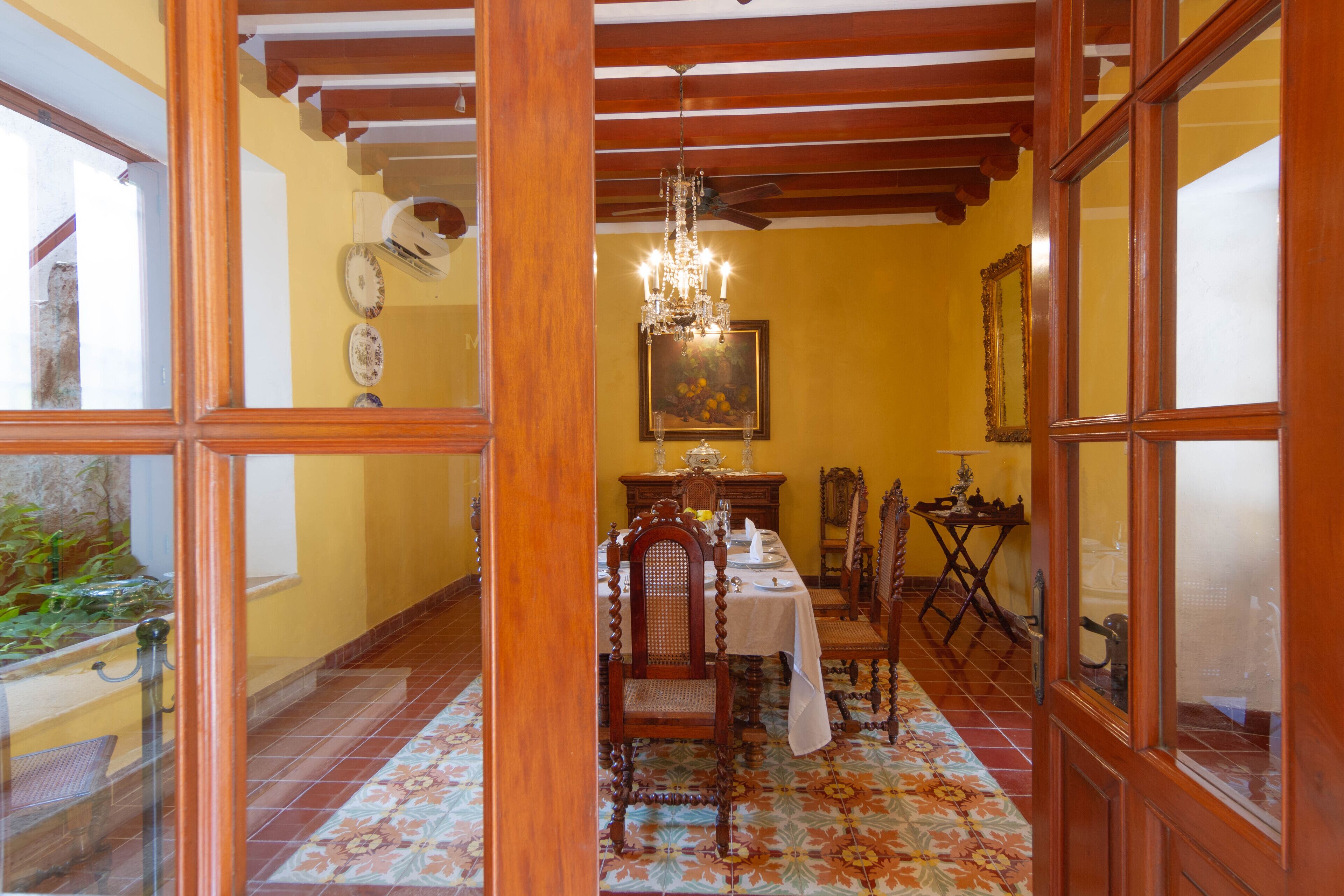 Zona pranzo con soffitto in legno, un lampadario e un tavolo apparecchiato per quattro persone.
