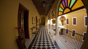 A corridor with a checkered floor, wooden doors, and a ceiling fan.