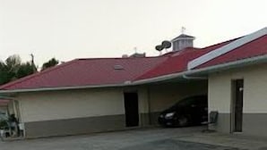 A building with a red roof and a large parking area. - Super 7 Inn Siloam Springs (Siloam Springs)