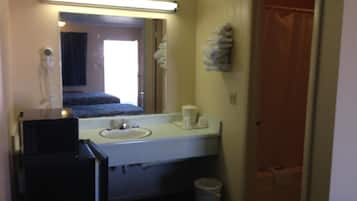 Un baño pequeño con lavamanos, espejo y barra para toallas.