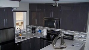 A modern kitchen with dark cabinets, stainless steel appliances, and a white countertop. - Water Street Inn (Boyne City)